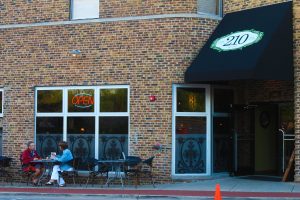 210 exterior frontage with cafe tables and awniing with logo